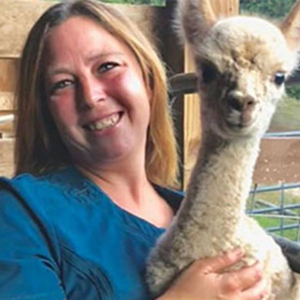Debbie, LVMT and Practice Manager, holding a light-colored alpaca