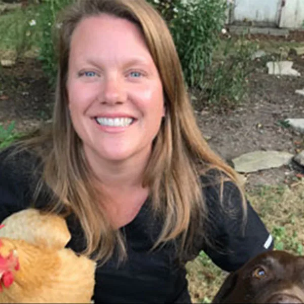 Dr. Jana Long, DVM, with a chicken and a brown dog